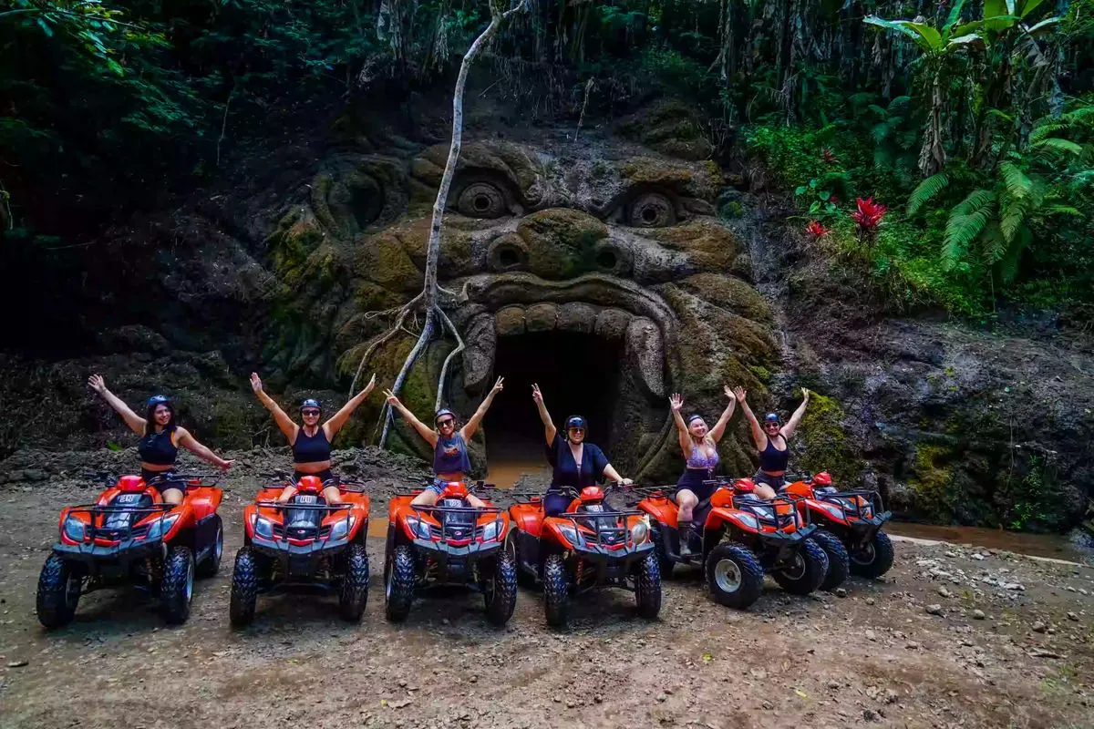 Group posing on red ATVs in front of Gorilla Cave