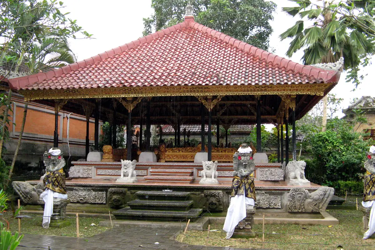Tiled performance pavilion with gamelan instruments and guardian statues at Ubud Palace.